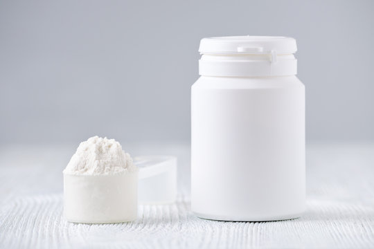mock up bottle and a spoon with powder, selective focus, on gray