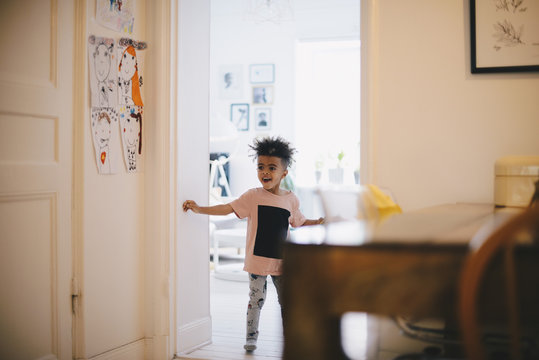 Smiling Boy Standing At Doorway Against Brightly Lit Room