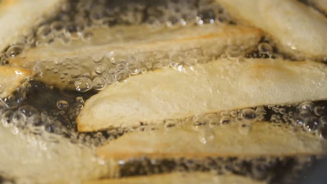 Potato slices fried in a frying pan in oil, slow motion