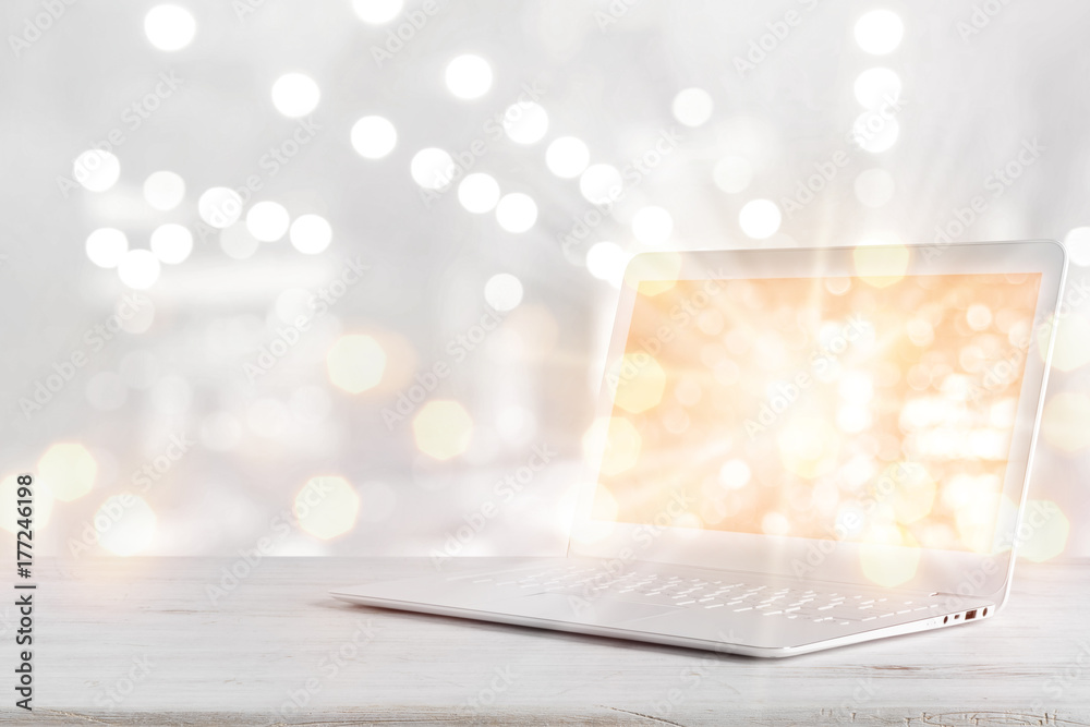 Wall mural laptop computer with glowing screen on table over abstract background