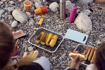 High angle view of woman and daughter preparing food on barbecue grill at beach