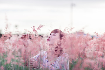 Beautiful young Asian women around the age of 30-40 years travelers feels happy and freedom Amid the Garden flowers pink grass in his holidays During his time at sunset .