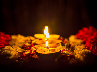 Happy Diwali - Diya lamps lit with flowers during diwali celebration.
