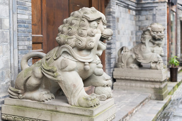 Two lion stone statues in front of a wooden door in KuanZhai narrow alley, Chengdu, China