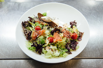 Caesar salad in a white plate on a metal surface