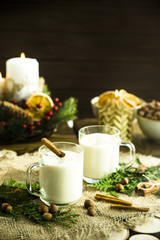 Obraz na płótnie Canvas hot milk alcoholic drink Egg-nog next to the Christmas candle and candles