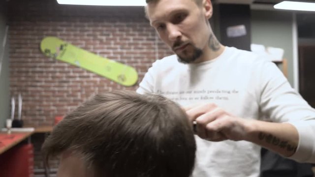 Adult barber at work with a new client in a beautiful barbershop 4k.