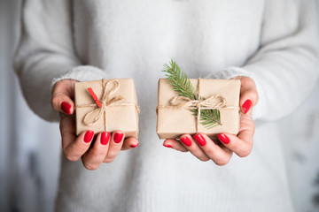 Woman's hands hold christmas or new year decorated gift box. Toned picture