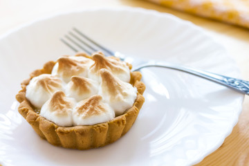 home made tartlet with meringue and lemon cream on a white plate,silver fork 