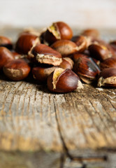 Roasted chestnuts on old wooden table. close up and selective focus. Autumn background 