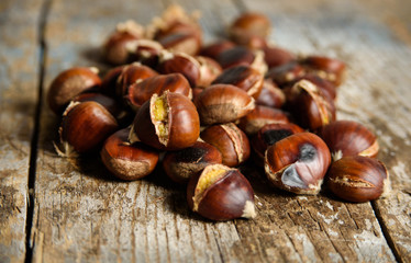 Roasted chestnuts on old wooden table. close up and selective focus. Autumn background 