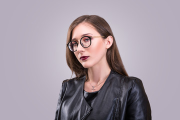 Beauty portrait of young attractive woman wearing glasses with agressive make-up dressed in laither jacket