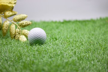 Golf ball with Christmas decoration on green grass, idea for golfer's Christmas holiday