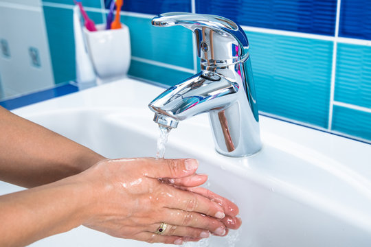 Woman cleans his hands in the bathroom.