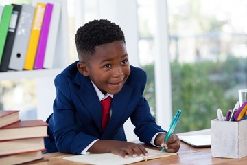 Smiling businessman looking away while writing on book