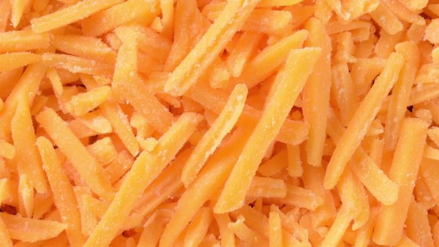 Overhead slide shot of grated cheddar cheese

