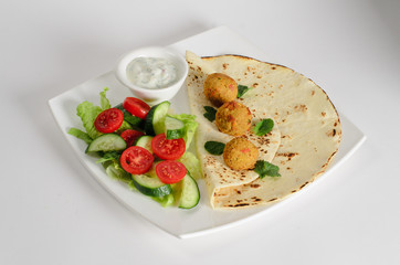Chickpeas balls with tortillas, white sauce and vegetable salad on a plate