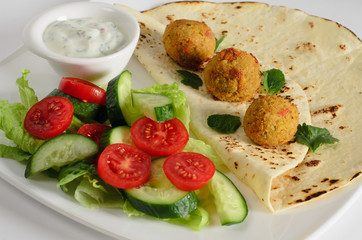 Chickpeas balls with tortillas, white sauce and vegetable salad on a plate