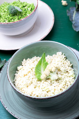 Cauliflower rice and broccoli rice in bowl on green background. Shredded.