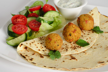 Chickpeas balls with tortillas, white sauce and vegetable salad on a plate