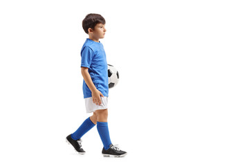 Little soccer player holding a football and walking
