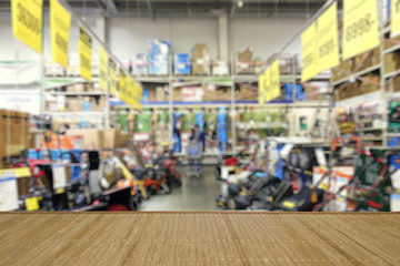 Shop of garden equipment. Lawn mowers. Defocused image. In the foreground is the top of a wooden...