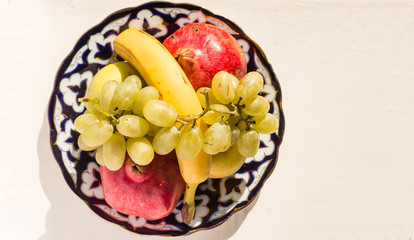 Golden apple, banana, pomegranate and grapes on a asian plate