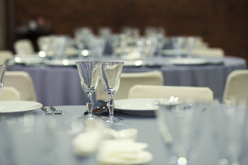 Preparation for a banquet. The tables are covered with a tablecloth. Wine glasses are on the tables in the restaurant.