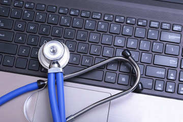 Blue stethoscope on a dark laptop computer