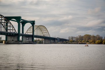 Obraz premium fishermen on an inflatable boat catching fish on the river at the bridge