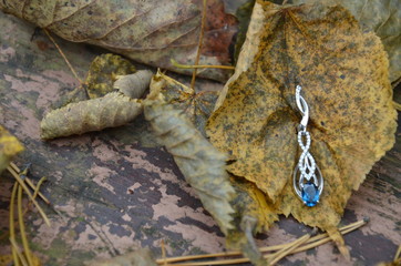 earrings. jewelry. with topaz or sapphire. large blue stone. on a vintage background. autumn. leaves