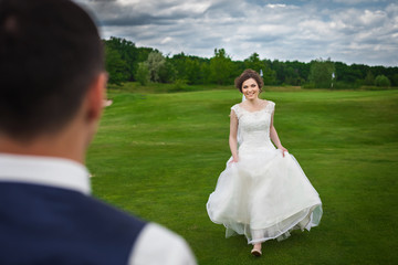 Bride is running to meet her groom on a meadow