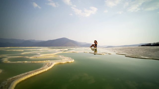 panoram on mineral nature pool with young women siting on the beautiful view, Mexico Hierve el Agua