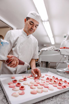 p&acirc;tissier pr&eacute;pare des macarons