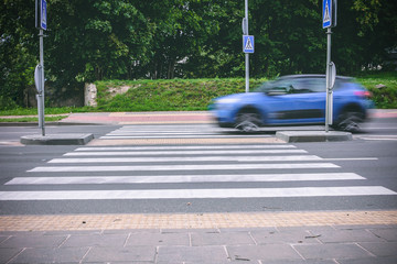 A blue car passing crosswalk
