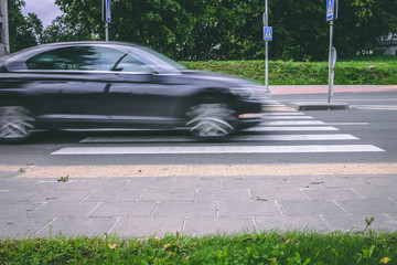A black car passing crosswalk
