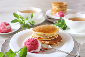 Two portions of banana pancakes with honey and fruit sorbet