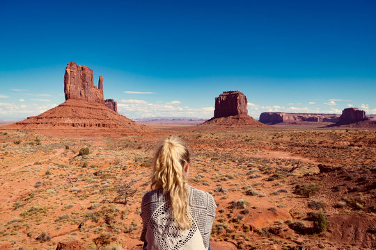 woman sitting in Monument Valley with red rocks overview