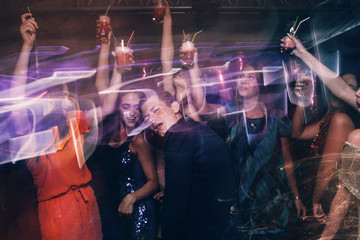 Happy company on dance floor. Joyful New Year in night club, active Christmas celebration in motion. Disco party in blurred colors, modern youth life, pickup concept