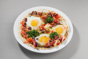 Fried eggs with sausages, pepper and beans on flatbread