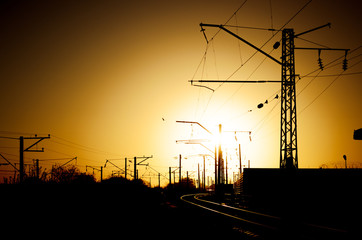 Railway - Railroad at sunset with sun, Rails and electric lines in yellow light