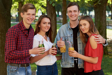 Group of happy young people enjoys detox cocktails and spend time together at summer. Friendship, youth lifestyle, vegetarian diet, fitness food on the go, successful weight loss concept