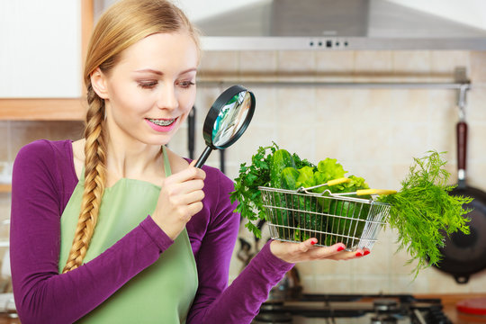 Woman looking through magnifier at vegetables basket