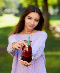Healthy lifestyle. Cute young woman with fresh beet smoothie jar, on green nature background. Diet, detox in summer, well being and weight loss concept