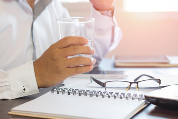 businessman holding glass of water and removing glasses on table, relax and healthy concept.