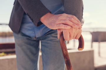 Close up of elderly males hands on a cane