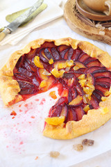 Homemade red plums tart galette, candied citrus garnish