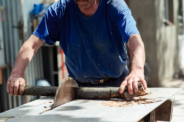 Man making firewood with buzz saw in the yard of a private house.