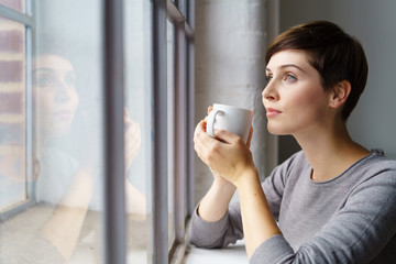 frau schaut nachdenklich aus dem fenster