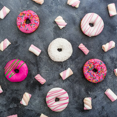Minimal pattern of colorful donuts with marshmallow on dark background. Delicious food. Flat lay, top view